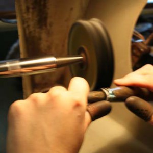 A jeweler holding a ring in front of a polishing wheel.